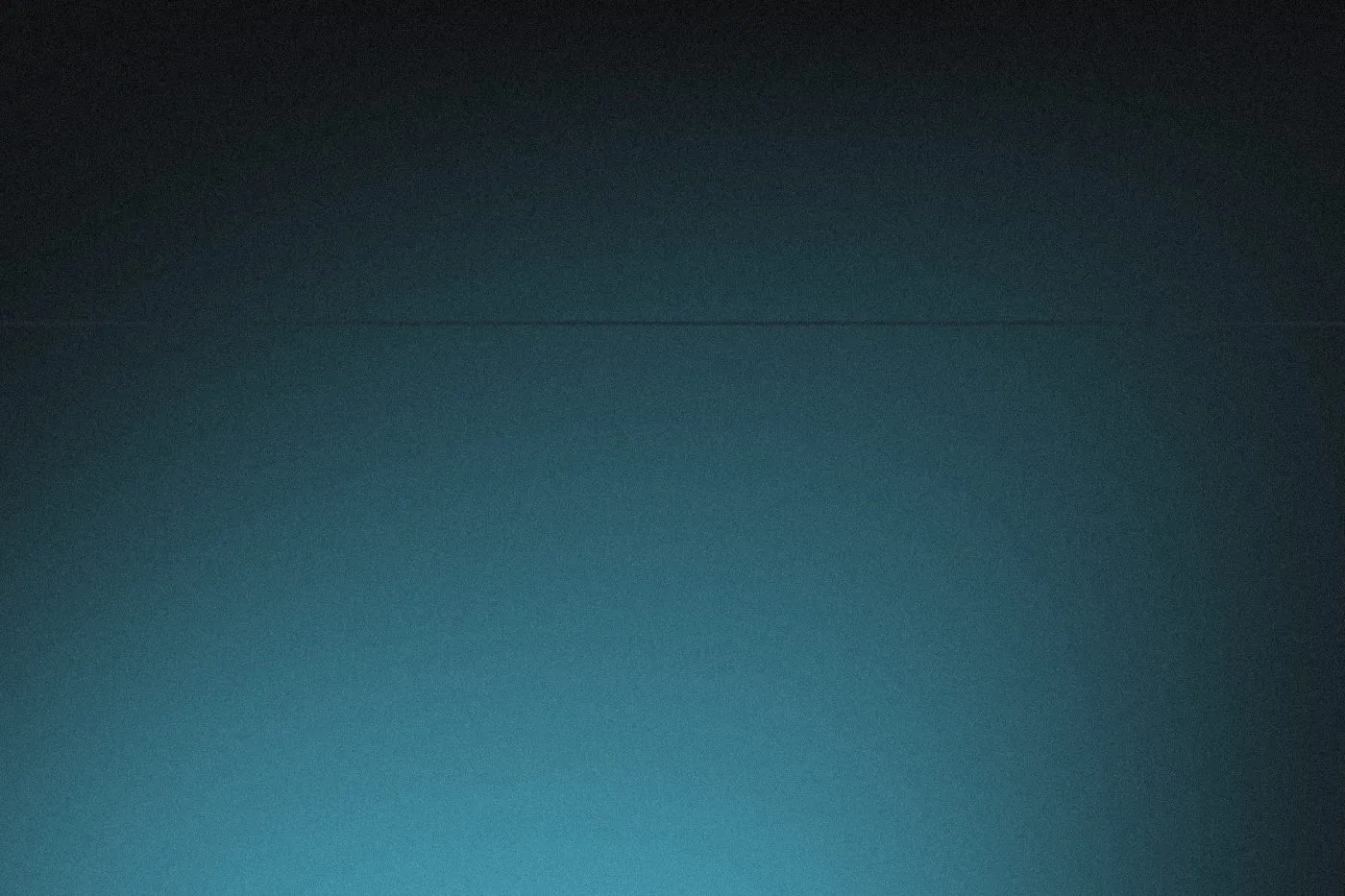 An empty studio wash of teal light, near-black across the top of the frame and brightening toward the bottom, with a faint horizontal seam a third of the way down where the wall meets the floor.